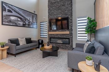 A living room with a grey couch, a coffee table, and a fireplace. at Vibe Apartments at Arbour Lake, Alberta